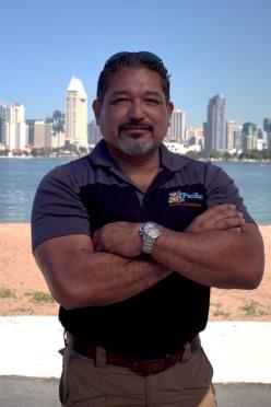 Pacific Heating and Air Conditioning technician posing confidently in front of the San Diego skyline, representing expertise and reliability.