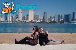 Two women posing back-to-back on a waterfront with the San Diego skyline behind them, featuring the Pacific Heating and Air Conditioning logo.