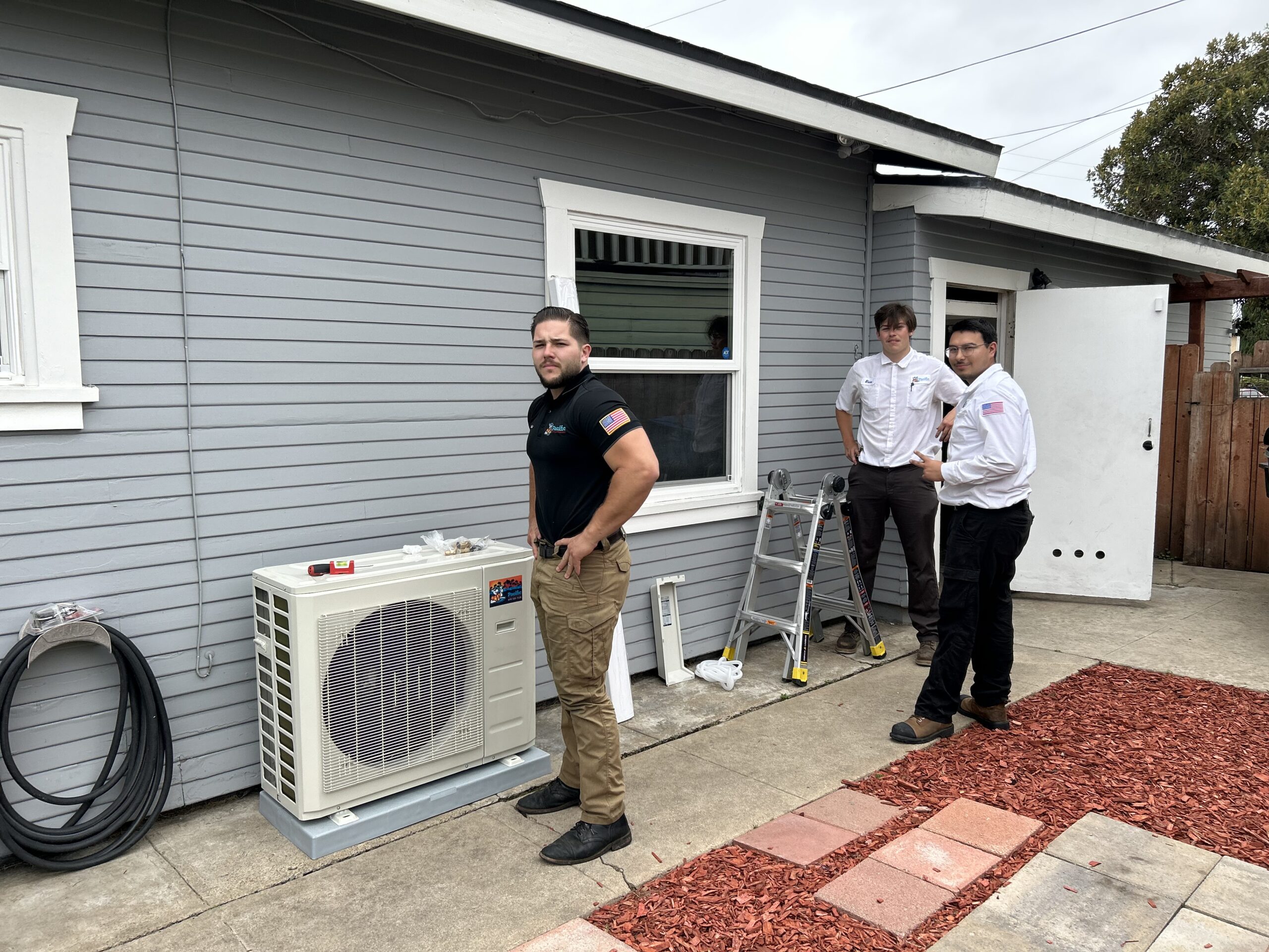 Pacific Heating and Air Conditioning technicians installing a ductless mini-split HVAC system at a residential home.